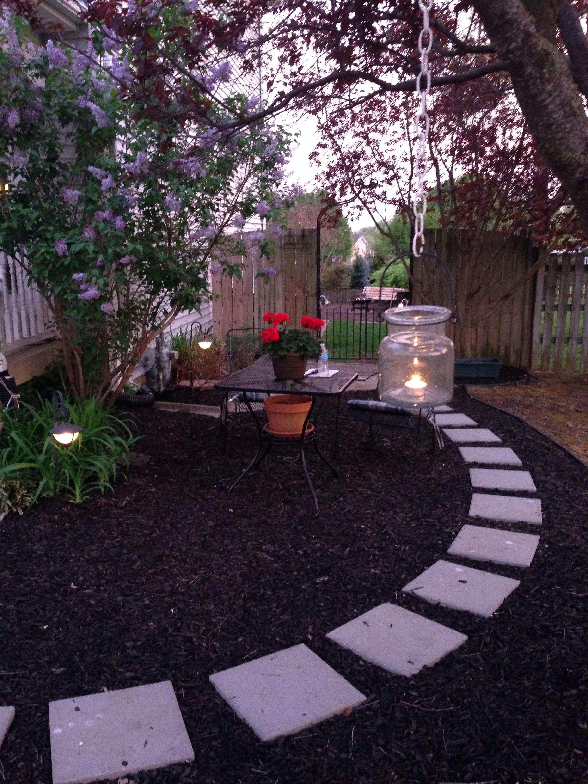 Evening shot of backyard garden with stepping stone path, flowering trees, and seating